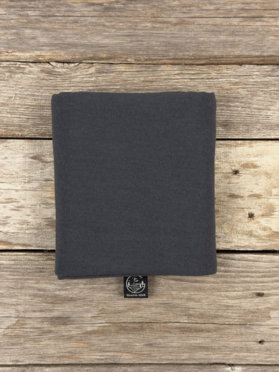 Sac à viande Glacial Gear en laine mérinos gris, plié, avec étiquette au logo sur du bois patiné