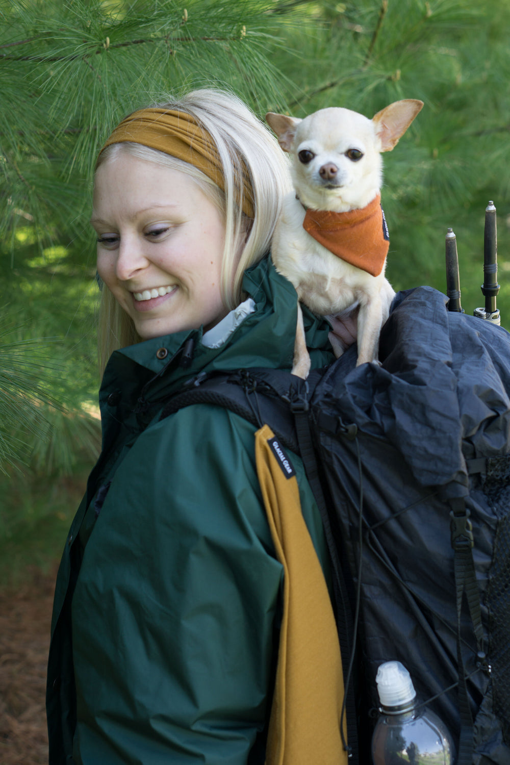 Randonneuse avec un chihuahua portant un Trail Rag Classic Paprika en bandana, et un second Trail Rag sur la bretelle de son sac