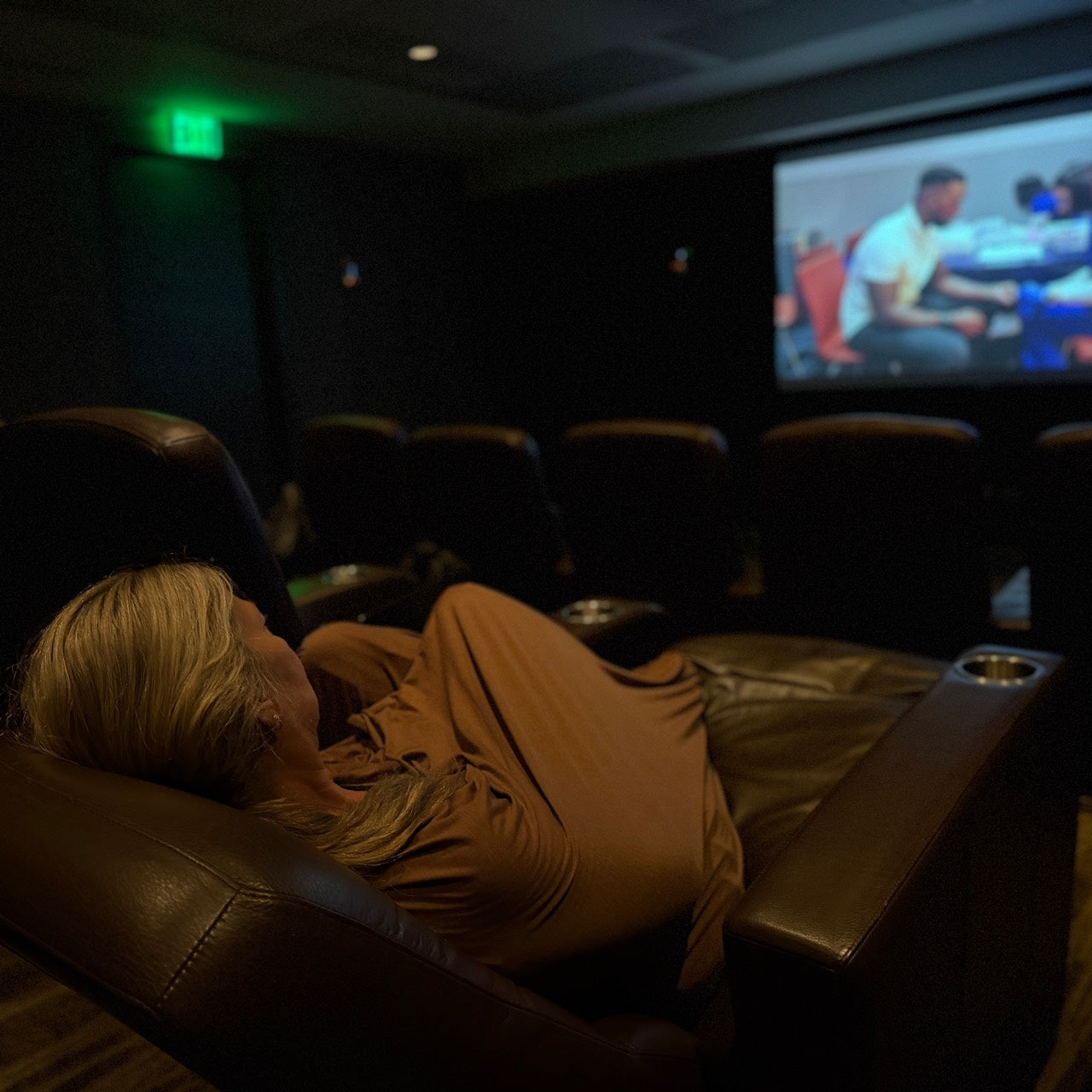Femme se détendant sous une couverture en laine mérinos Bark dans un fauteuil inclinable de cinéma