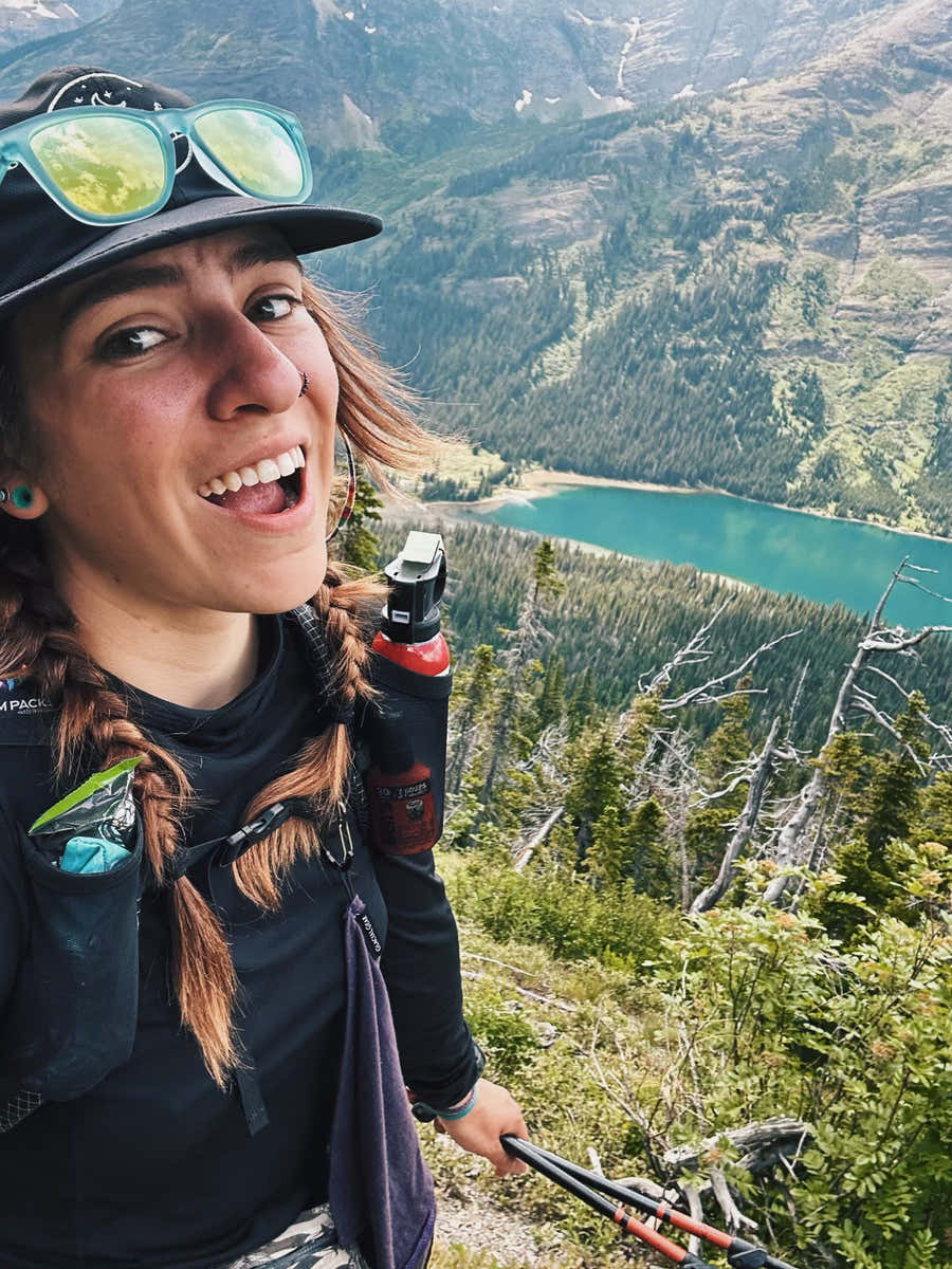 Backpacker with a purple Trail Rag Classic overlooking an alpine lake