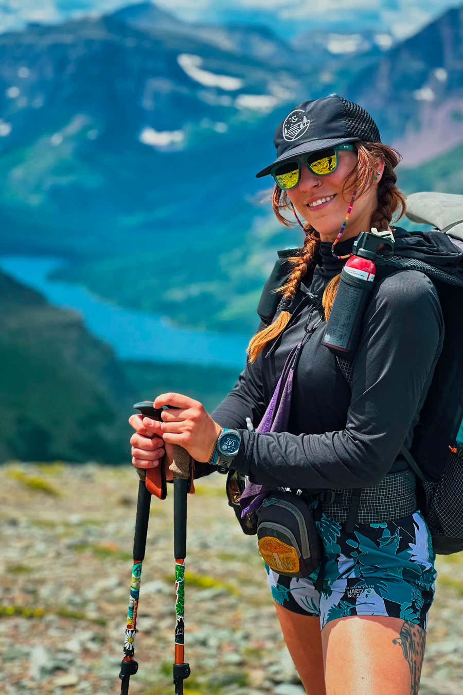 Backpacker wearing a black Glacial Gear Foldable Trail Hat above a blue mountain lake