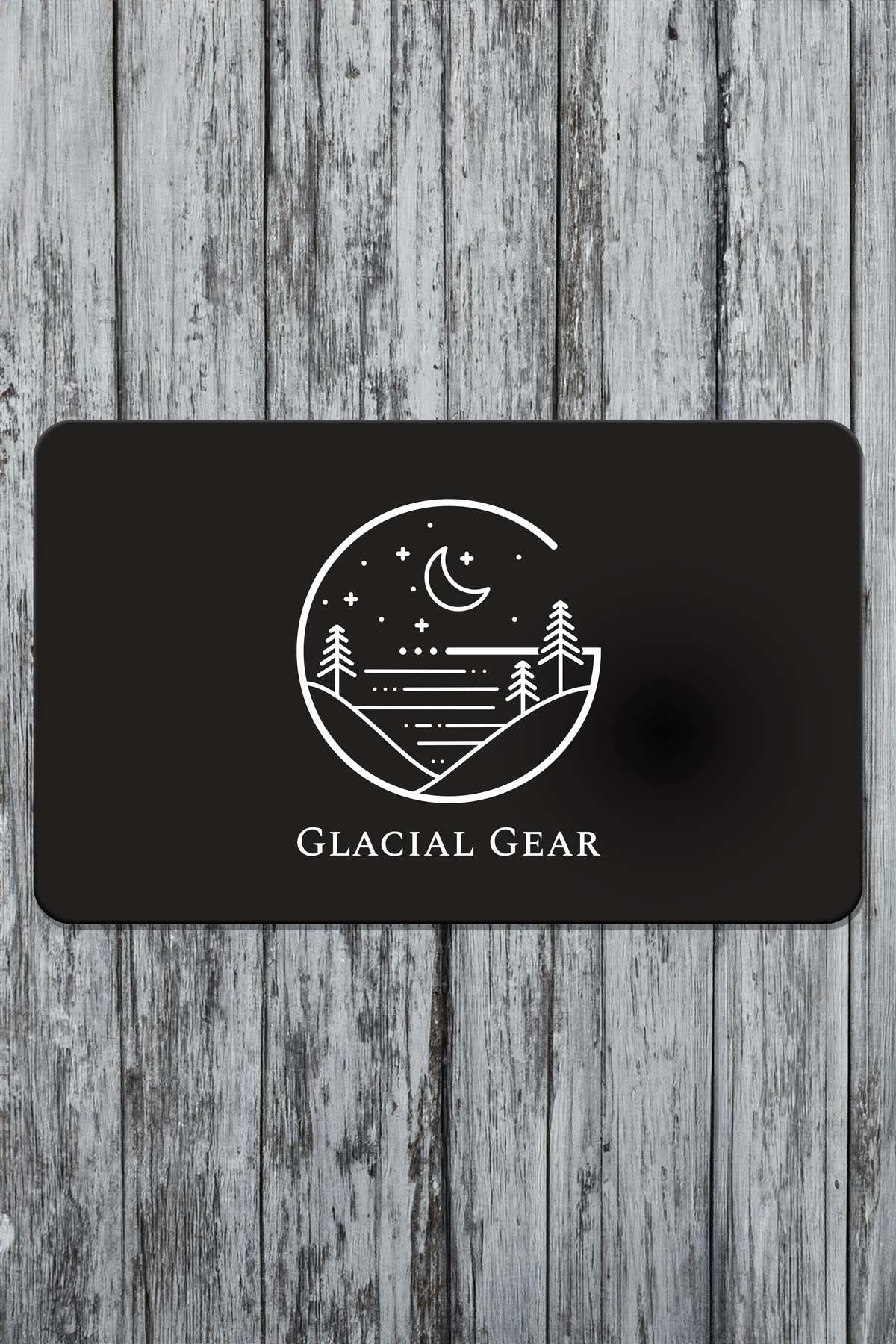 Black Glacial Gear gift card with white hammock, mountain, and moon logo on weathered wood