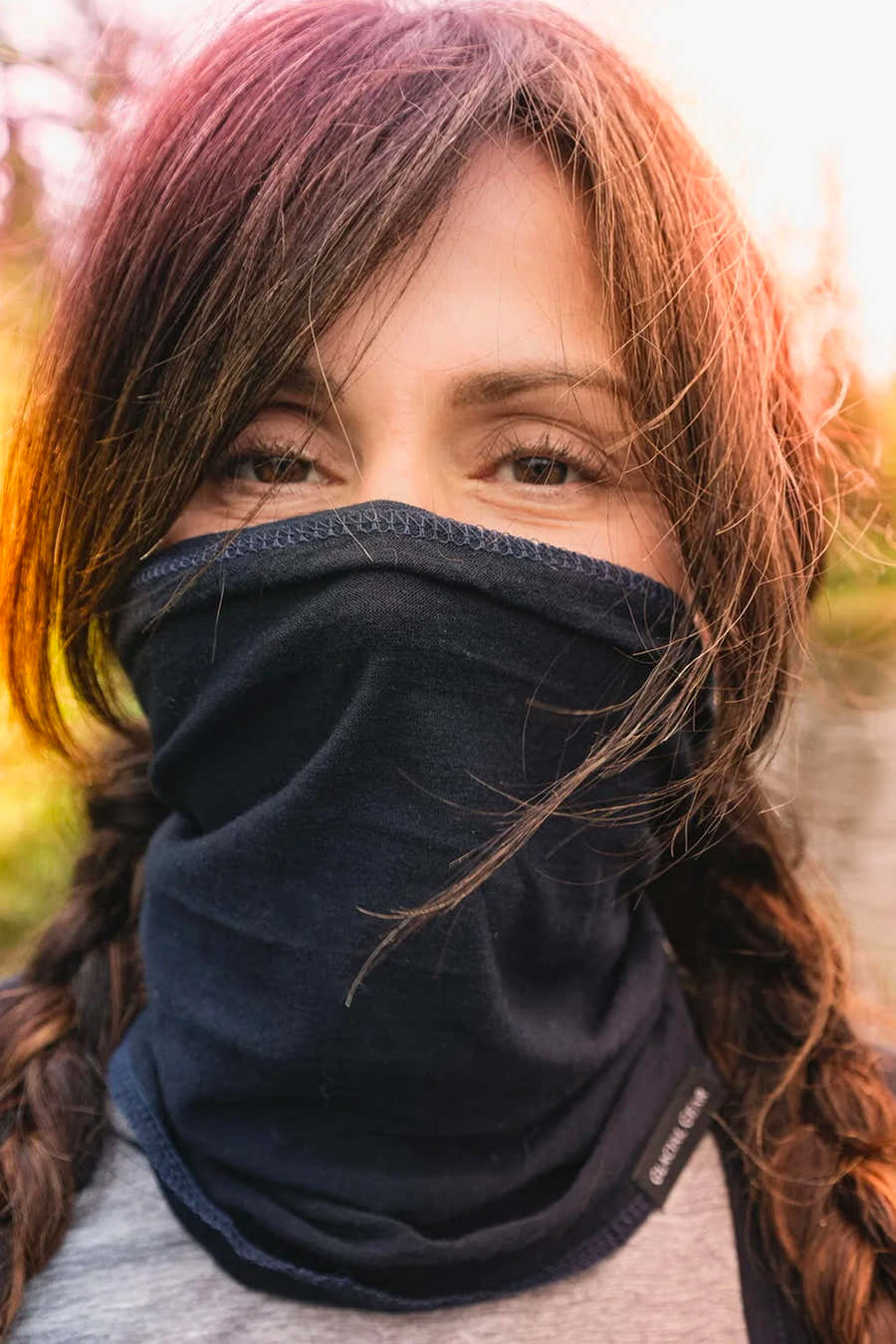 Woman wearing a black Glacial Gaiter over her nose and mouth outdoors
