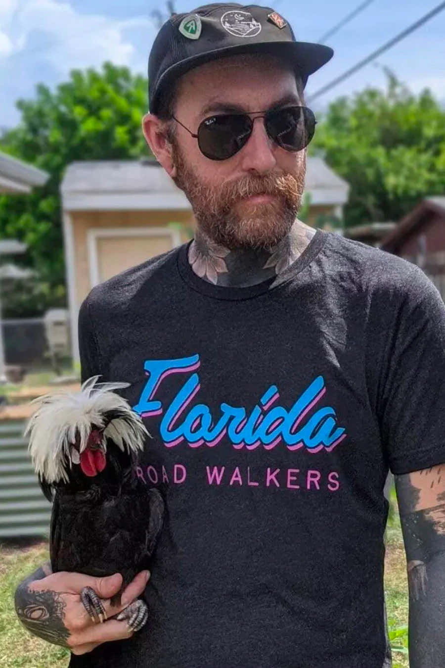 Man wearing a Glacial Gear logo cap and sunglasses while holding a crested chicken