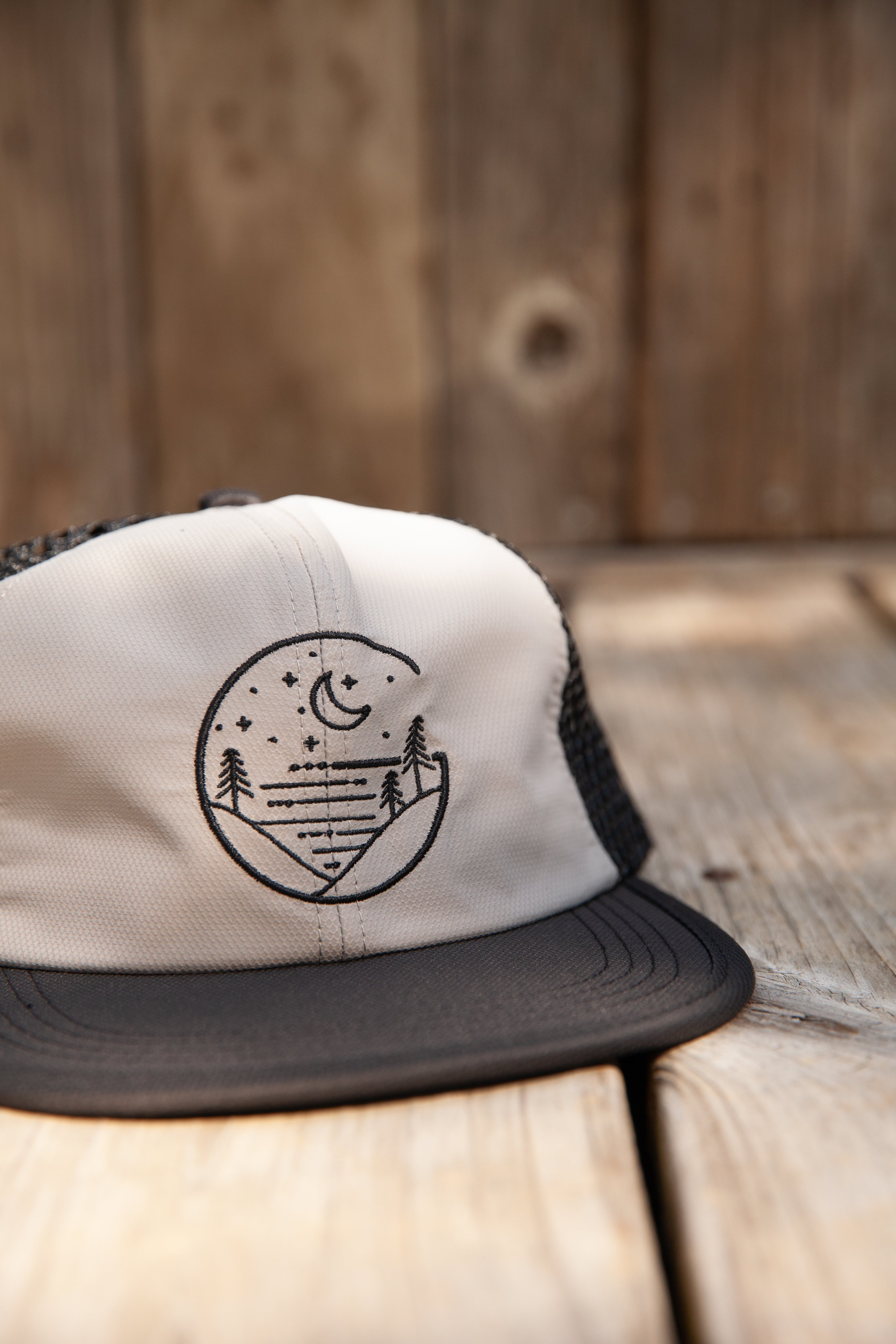 Gray Glacial Gear Foldable Trail Hat with black brim and mesh sides on weathered wood
