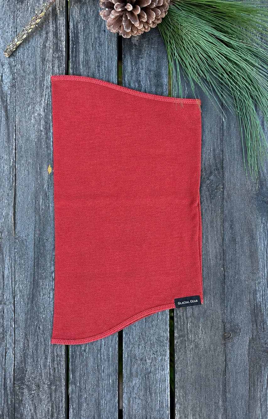 Red Glacial Gaiter Merino wool neck gaiter laid flat on weathered wood