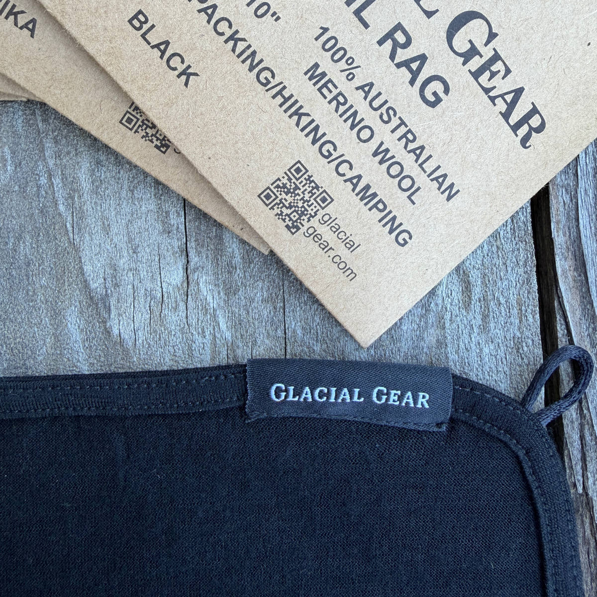Trail Rag couleur Black avec bord arrondi et boucle d’accrochage, à côté de l’emballage Glacial Gear