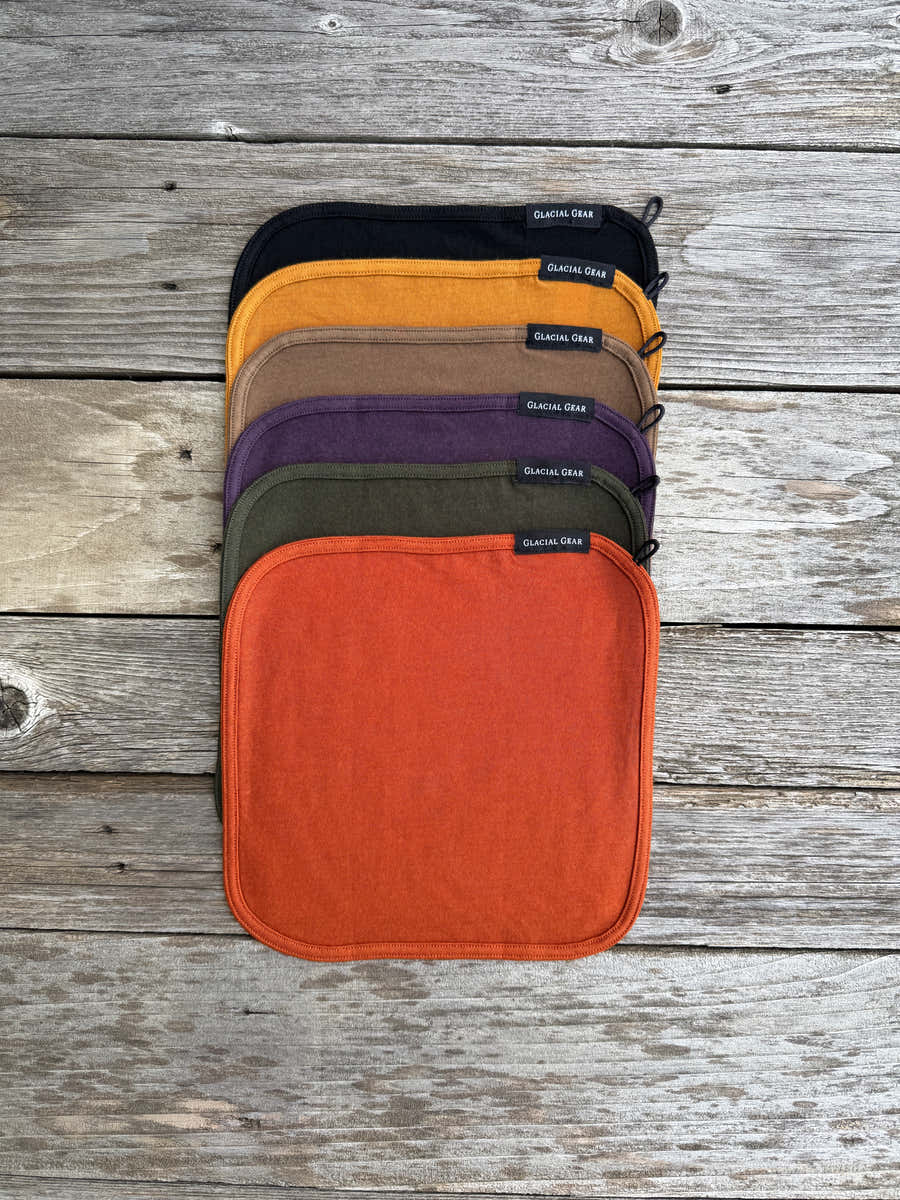 Glacial Gear Merino wool Trail Rags stacked in six colors on weathered wood