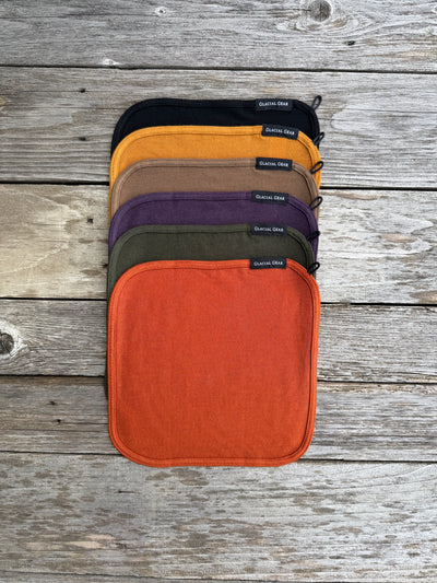 Glacial Gear Merino wool Trail Rags stacked in six colors on weathered wood
