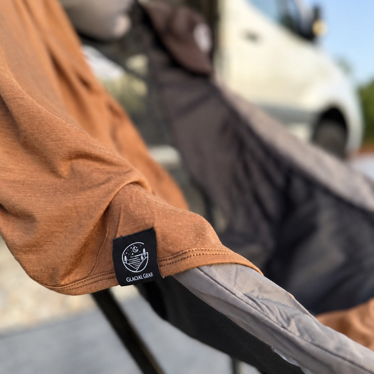 Bark Merino wool blanket draped over a camping chair, showing the Glacial Gear label and stitched hem