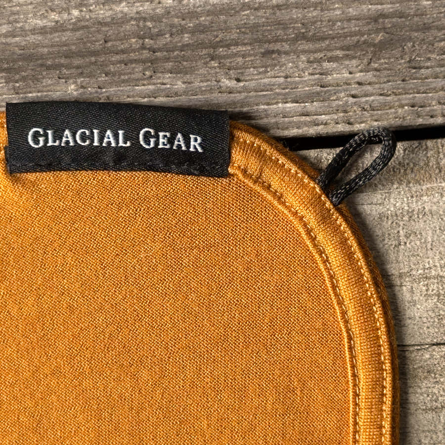 Close-up of a Mustard Merino wool Trail Rag showing the fine knit, stitched rounded edge, hanging loop and Glacial Gear label
