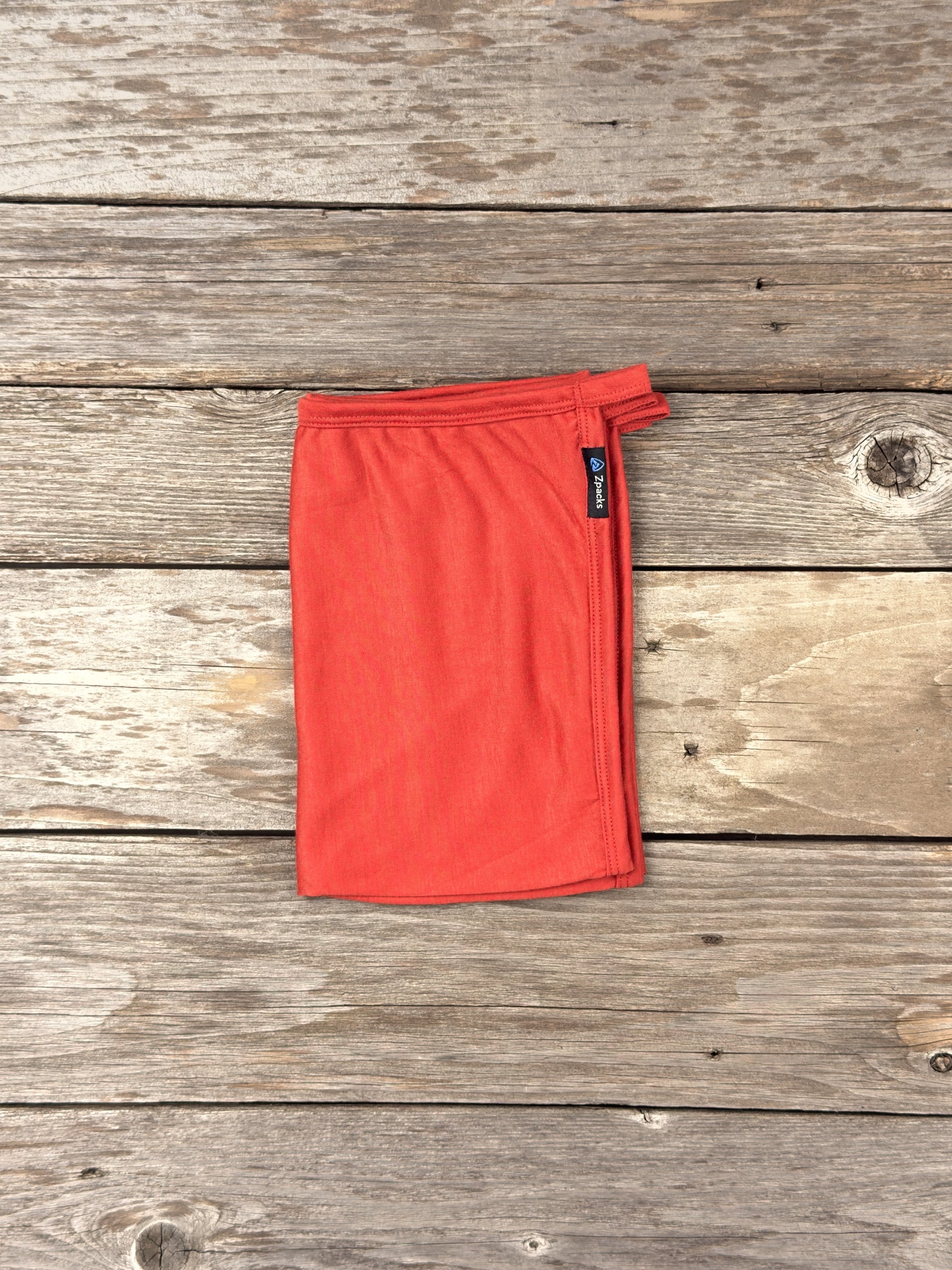 Medium Autumn Glacial Gear x Zpacks Camp Towel, folded on weathered wood