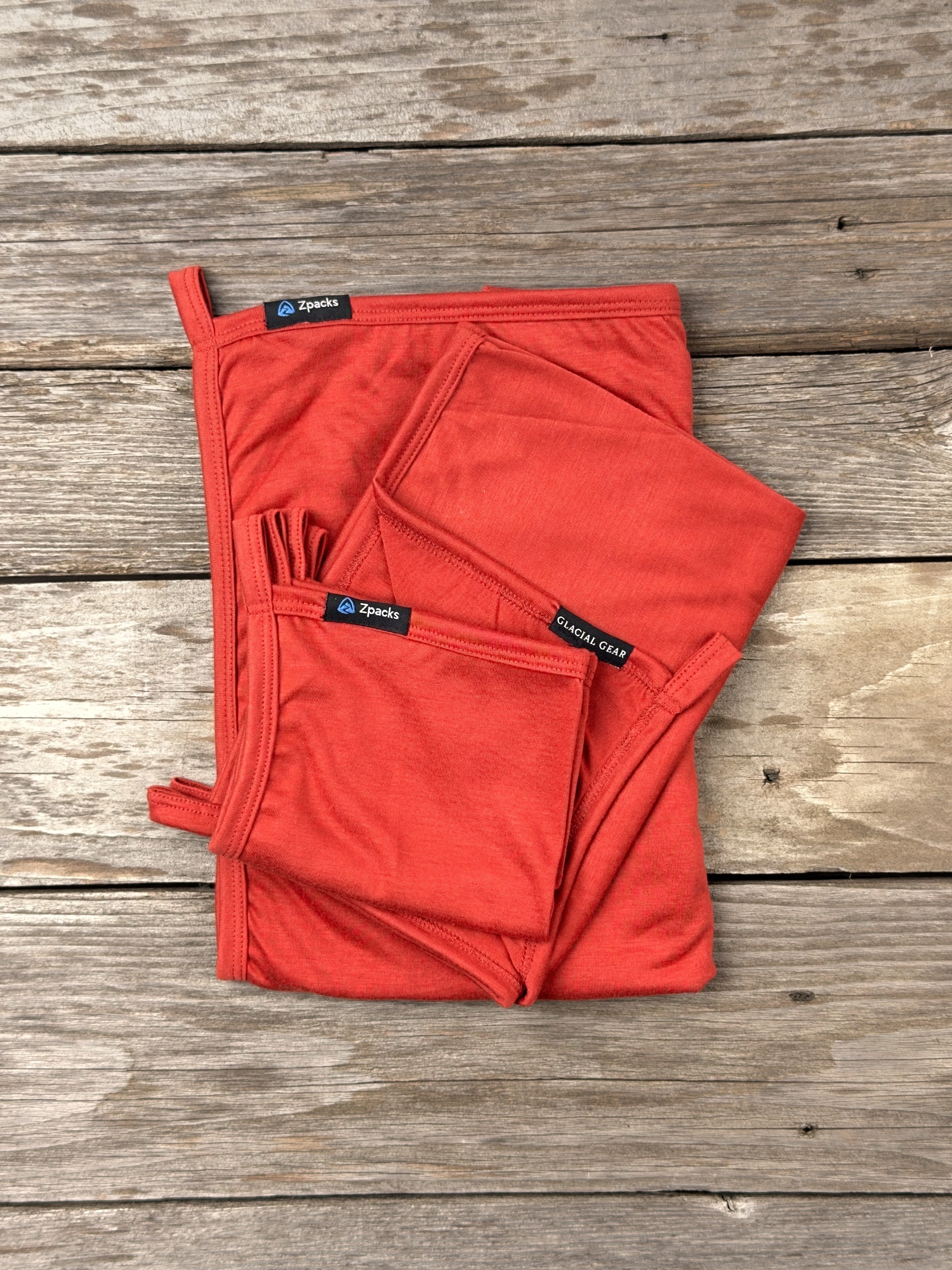 Glacial Gear x Zpacks Camp Towels in Autumn, folded in Small, Medium and Large on weathered wood