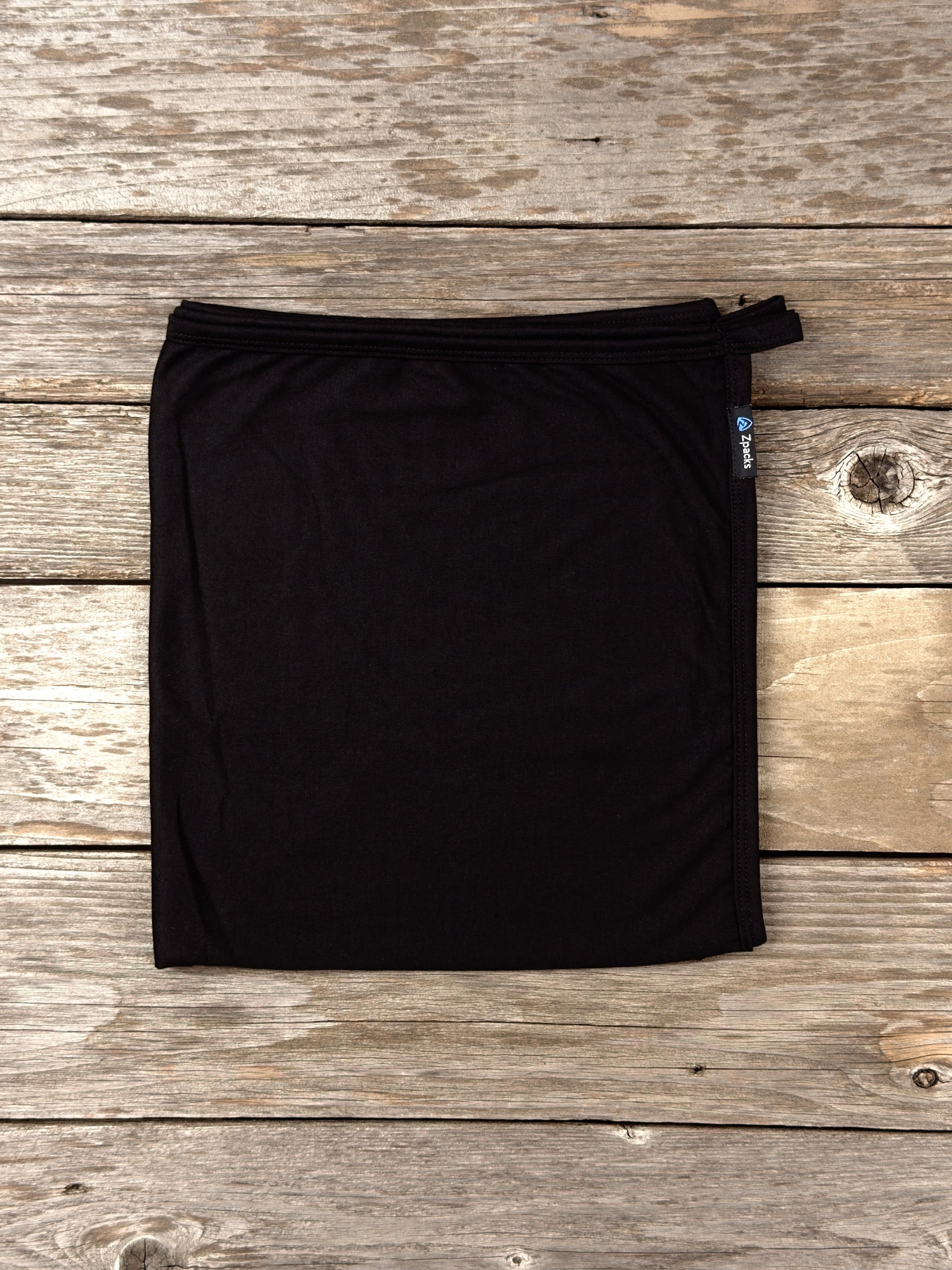 Large Black Glacial Gear x Zpacks Camp Towel, folded on weathered wood