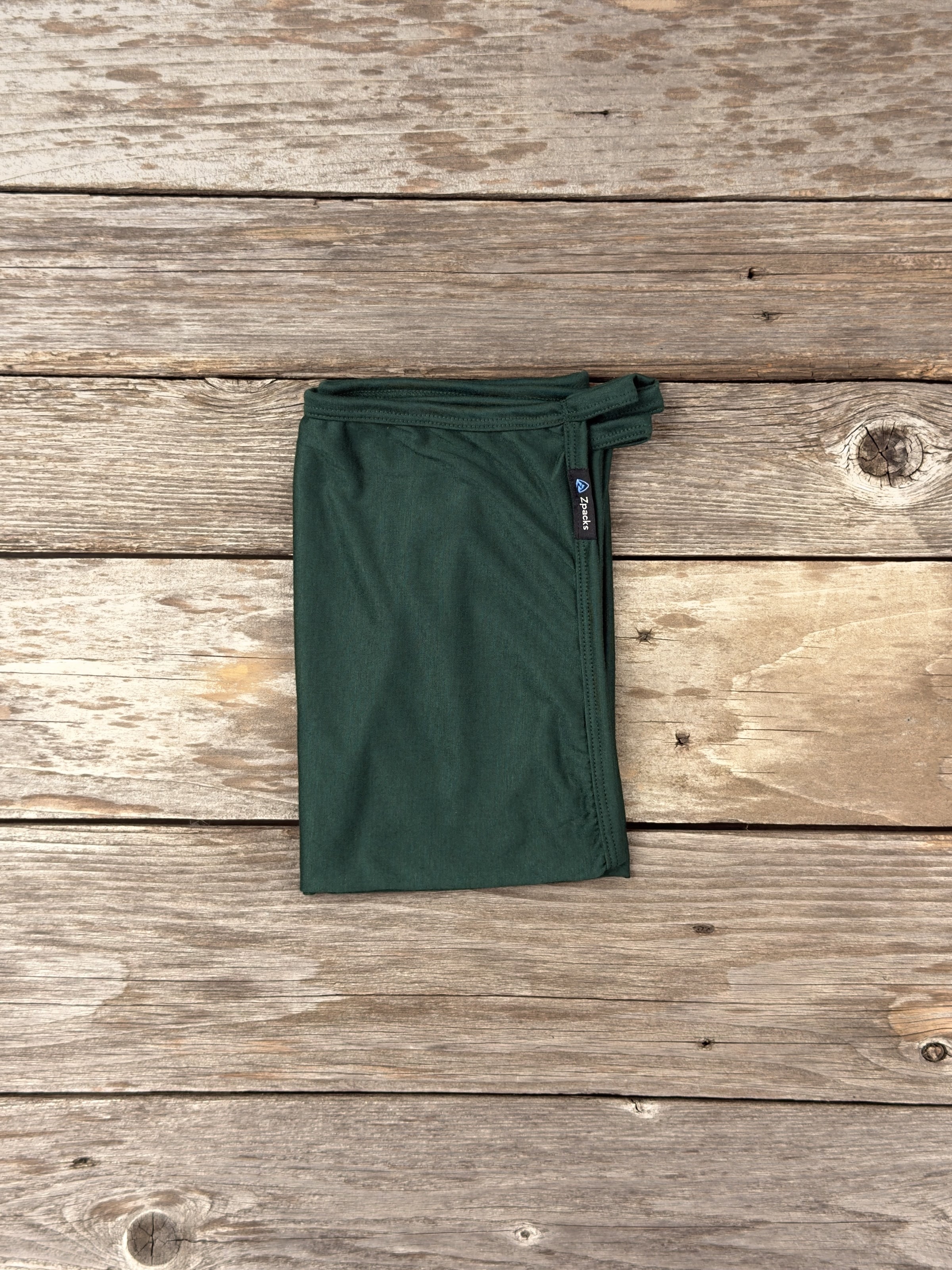 Medium Forest Glacial Gear x Zpacks Camp Towel, folded on weathered wood