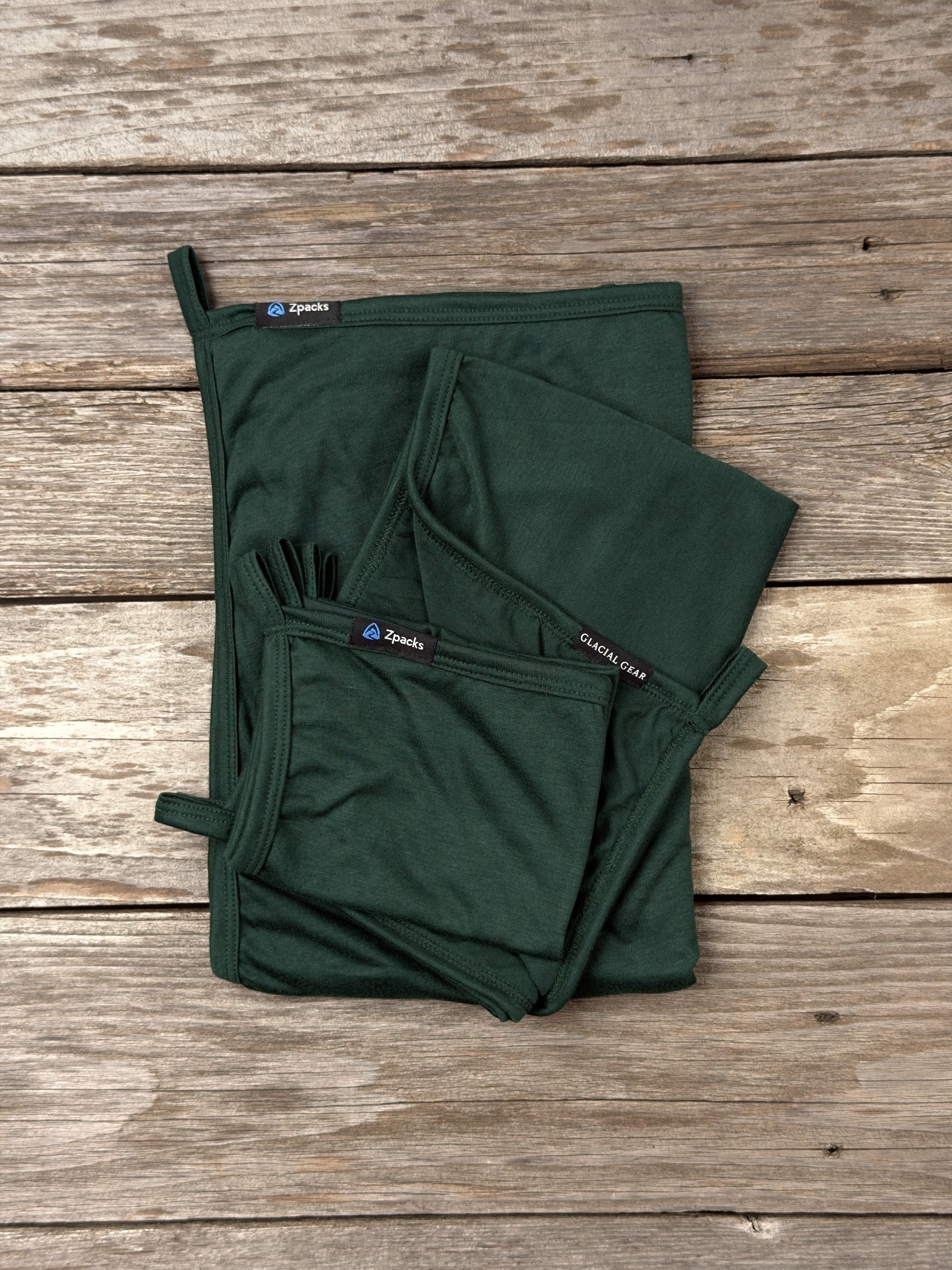 Glacial Gear x Zpacks Camp Towels in Forest, folded in Small, Medium and Large on weathered wood