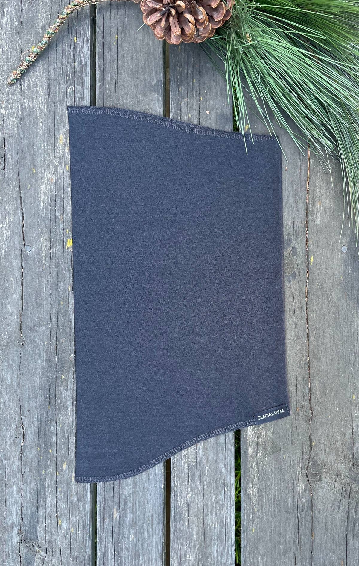 Gray Glacial Gaiter Merino wool neck gaiter laid flat on weathered wood